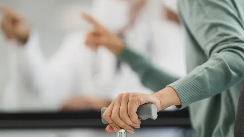 Une main posée sur une canne, pendant une consultation.
